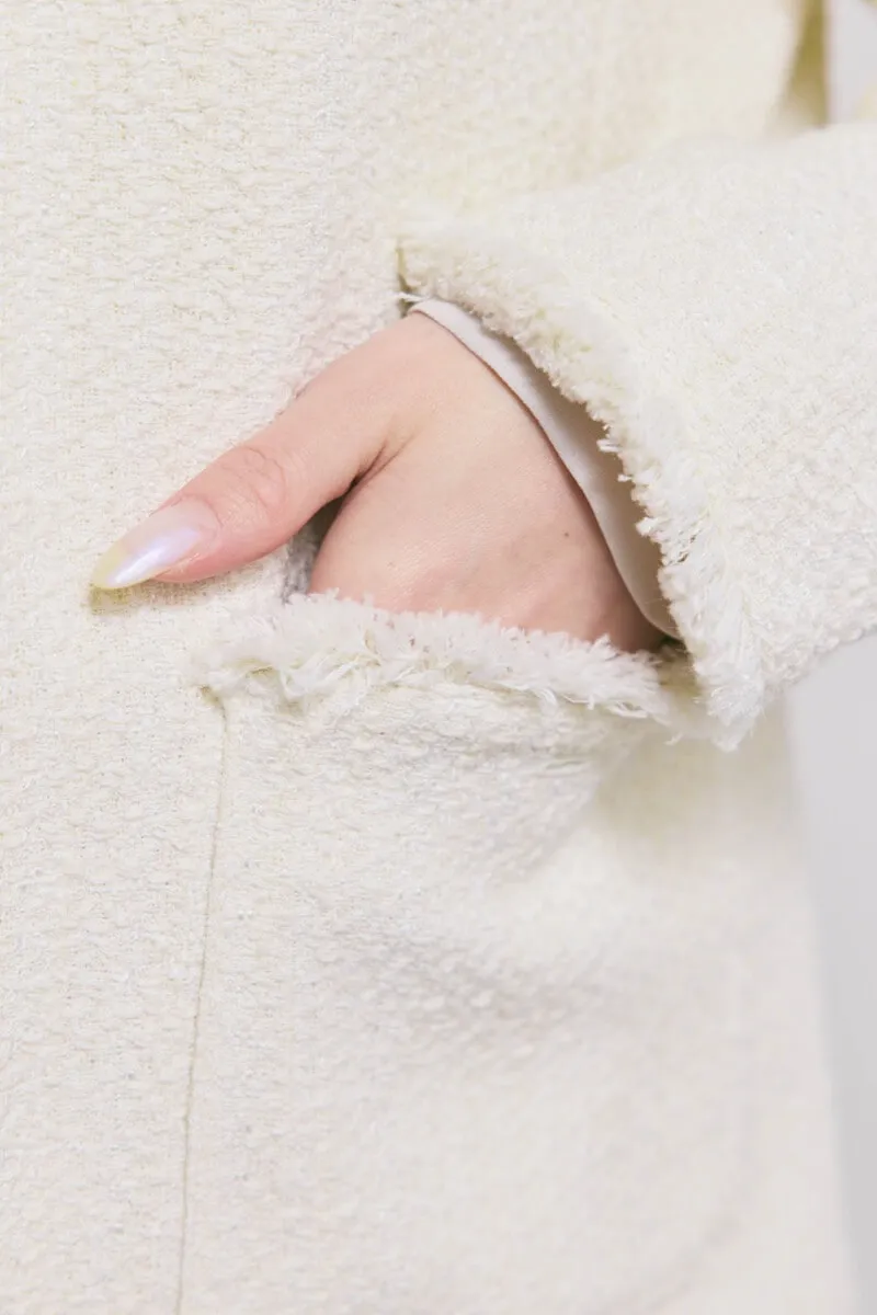 オフホワイトのツイードライクノーカラージャケット